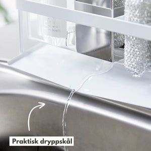 Nærbilde av hvit såpeholder i bruk ved kjøkkenvask.
