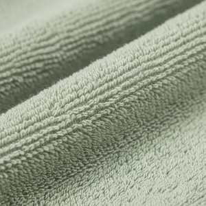 Friskt grønt badehåndkle hengende i moderne baderom