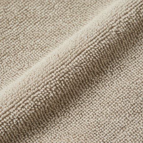 Nøytralt beige badehåndkle hengende i moderne baderom