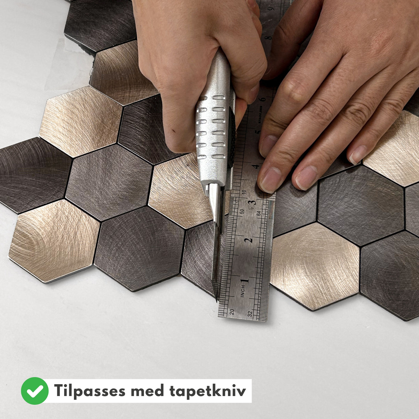 Hender som monterer latte hexagon selvklebende fliser på vegg.