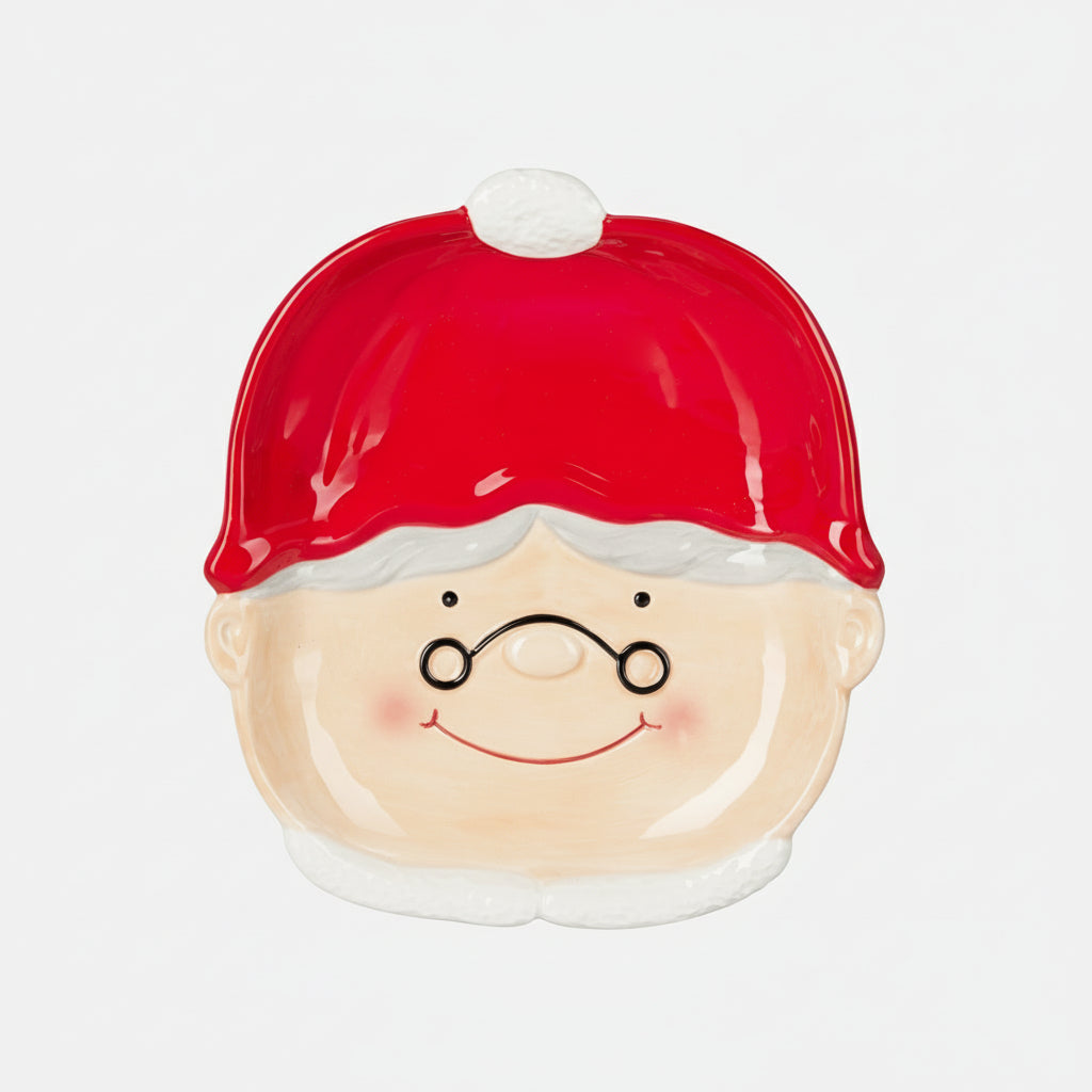 Dekorativ tallerken med nisseansikt på hvit duk med julepynt