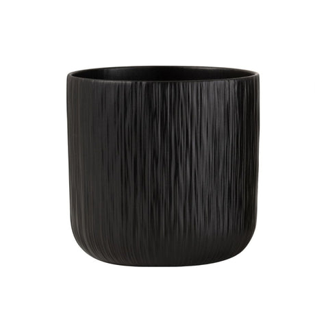 To sorte keramiske blomsterpotter, en glatt og en strukturert, på tregulv i moderne stueinteriør