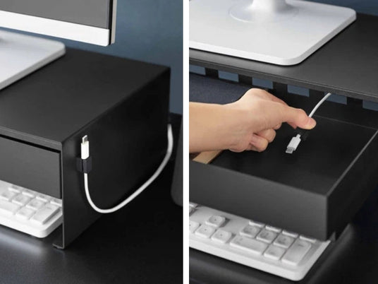 Nærbilde av magnetisk kabelholder på siden av monitorstativ sort og hånd som fører kabel gjennom utsparinger under stativet