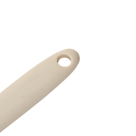 Nærbilde av beige silikonhåndtak med praktisk hull for oppheng av slikkepotten.