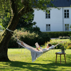 Luessa hengekøye i off white med frynser spent opp i hagen