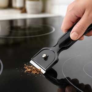 Nærbilde av GastroMax skrape i bruk på induksjonstopp med fastsittende matsøl
