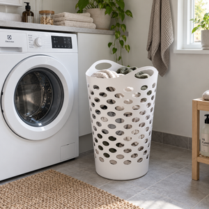 Hvit fleksibel vaskekurv 60 liter, 45 x 66 cm, med håndtak og perforert design ved vaskemaskin.