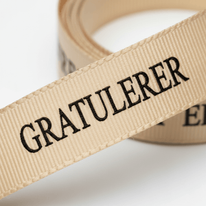 Beige pyntebånd med sort tekst for dekorative gaver