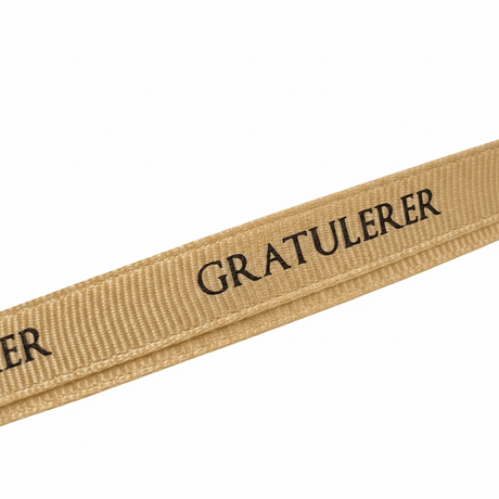 Nærbilde av beige grosgrainbånd med sort «Gratulerer»-tekst. - Lindas dekor