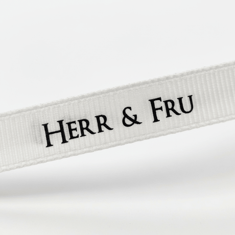 Nærbilde av hvitt gavebånd med sort «Herr & Fru»-tekst som viser tekst, struktur og bredde tydelig. - Lindas dekor 