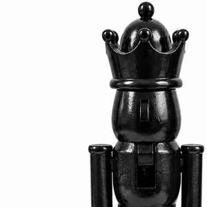 Nærbilde av svart nøtteknekkerfigur med blank overflate, dekorativ krone og detaljer i ansikt og uniform.