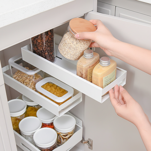 Uttrekkbar smal hylle i hvit metall montert inni kjøkkenskap