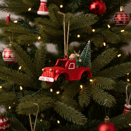 Röd metallbil med ett God Jul-skylt som nostalgisk trädpynt