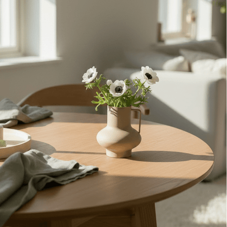 Dekorativ sandfarget vase med blomster på spisebord i lyst skandinavisk interiør