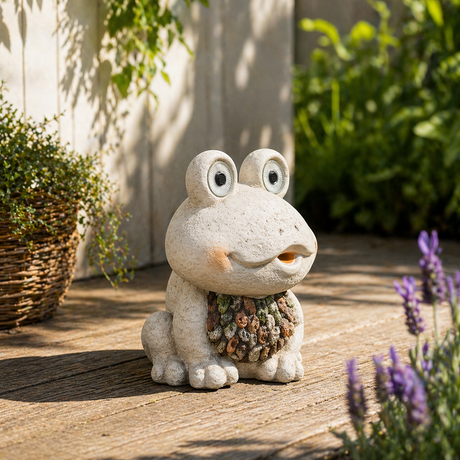 En dekorativ froskefigur plassert i en frodig hage med grønne planter og jord rundt