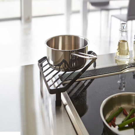 Svart komfyrhjørne stativ til gryter og panner ved platetopp