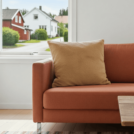 Dekorativt putetrekk i beige pelslook på terrakottafarget sofa