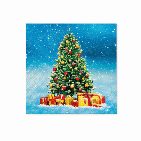 Juleservietten med et motiv af et pyntet juletræ omgivet af gaver mod en blå snøhimmel