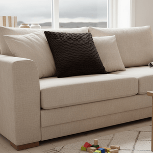 Sort pyntepute i velur på hvit sofa med lyse tekstiler