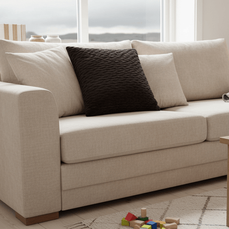 Sort pyntepute i velur på hvit sofa med lyse tekstiler