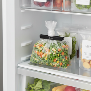 Svart poseklips som lukker frysepose med grønnsaker i kjøleskap – holder maten fersk og organisert