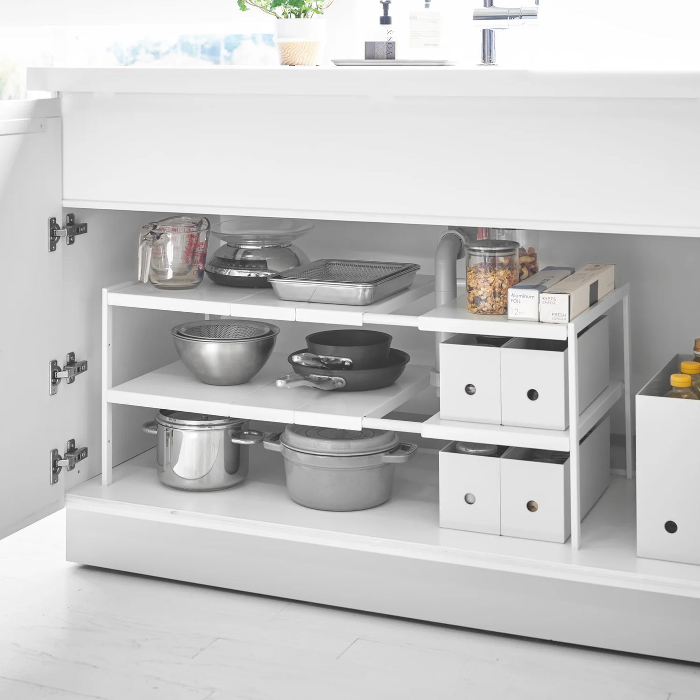 Under vask hylle med to nivåer for rengjøringsmidler og flasker